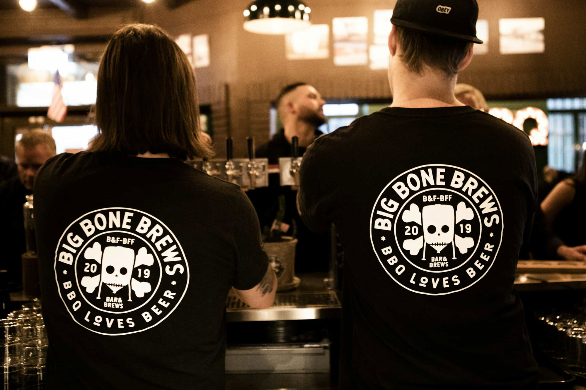 Två kollegor med Big Bone Brews-tröjor i baren